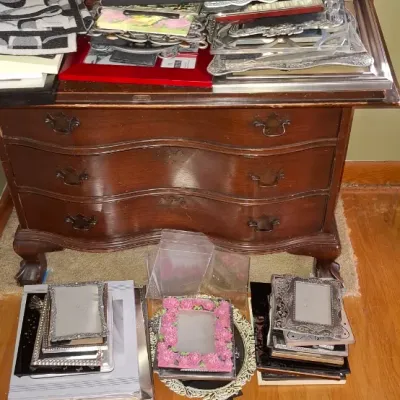 Sale Photo Thumbnail #73: Vintage dark wood slant-front secretary desk with claw and ball feet, filled with stacks of books, framed art, and decorative picture frames.