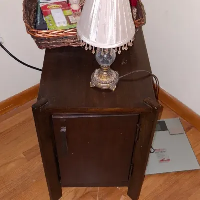 Sale Photo Thumbnail #21: Dark wood single-door nightstand paired with a small beaded table lamp, wicker basket, and plush teddy bear.