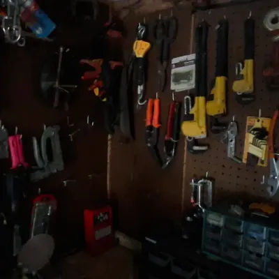 Sale Photo Thumbnail #140: Workshop corner featuring pegboard walls hung with various hand tools, including pliers, clamps, and scrapers, alongside small-parts storage organizers.