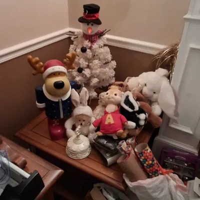 Sale Photo Thumbnail #117: Collection of holiday plush toys and decor, including an Alvin Seville stuffed animal, a dog reindeer figure, a white Christmas tree snowman, and rolls of gift wrap.