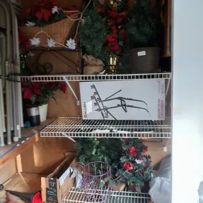 Sale Photo Thumbnail #136: Storage shed area featuring faux holiday greenery, an Allen bike carrier box, and a red push lawn mower on the floor.
