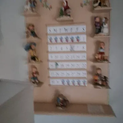Sale Photo Thumbnail #96: Vintage M.J. Hummel wooden perpetual calendar display board, featuring small shelves holding various collectible figurine pieces.