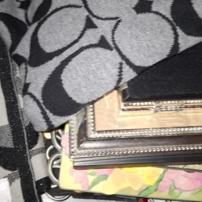 Sale Photo Thumbnail #77: Coach brand black and gray signature C logo knit scarf, resting on a stack of small picture frames and books.