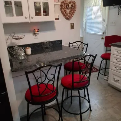 Sale Photo Thumbnail #46: Set of wrought iron counter-height barstools with red upholstered cushions, paired with a dark granite-topped peninsula table.
