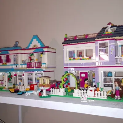 Sale Photo Thumbnail #119: Collection of assembled Lego Friends house and building sets with accompanying mini-dolls and toy vehicles arranged on a white shelf.