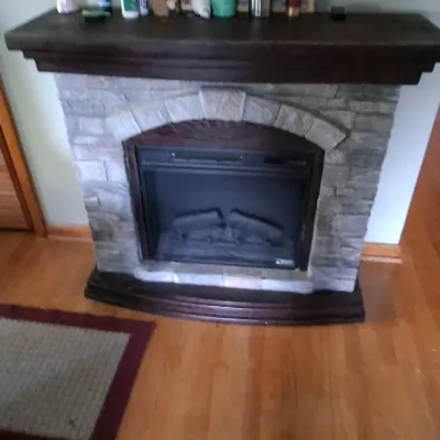 Sale Photo Thumbnail #93: Freestanding electric fireplace heater featuring a faux stone veneer surround and dark wood mantle shelf.