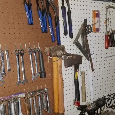 Sale Photo Thumbnail #144: Pegboard wall organization displaying a wide assortment of hand tools and Ryobi power tools, including wrenches, pliers, hammers, and a reciprocating saw.