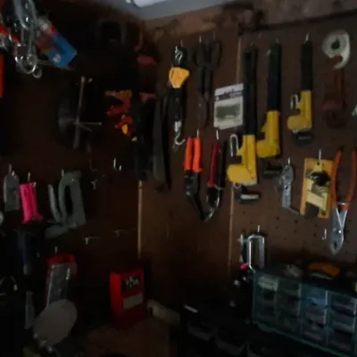 Sale Photo Thumbnail #137: A workshop pegboard wall heavily lined with various hand tools, including pliers, pipe wrenches, wire cutters, and small hardware storage cabinets.