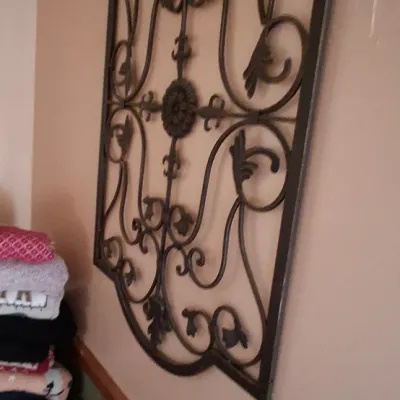 Sale Photo Thumbnail #81: Large Tuscan-style wrought iron metal scrollwork wall decor panel mounted on a wall.