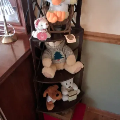 Sale Photo Thumbnail #88: Dark wooden five-tier corner shelf filled with stuffed animals, including teddy bears and a plush duck.