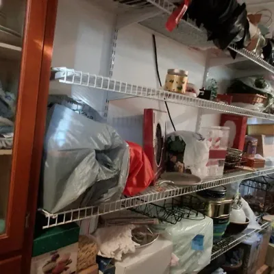 Sale Photo Thumbnail #105: Storage area featuring wall-mounted wire shelving units filled with various household goods, linens, and decor items alongside a wooden cabinet.
