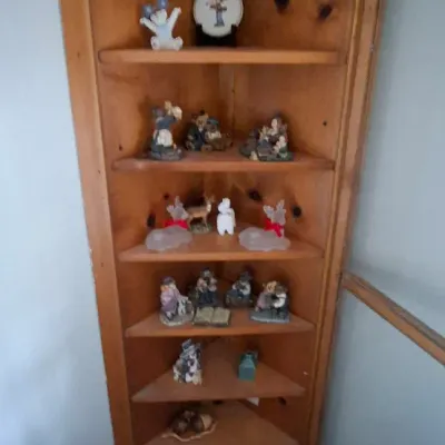 Sale Photo Thumbnail #97: Tall rustic knotty pine corner hutch featuring multiple open shelves filled with various decorative porcelain and resin figurines.