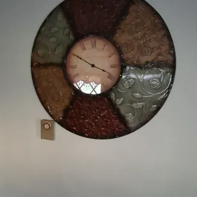 Sale Photo Thumbnail #94: Large decorative wall clock with embossed metal multi-colored panels surrounding a central face with Roman numerals.