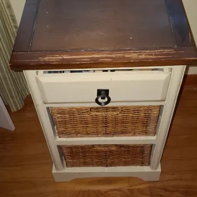 Sale Photo Thumbnail #25: Two-tone accent table featuring a dark wood top, a top pull-out drawer with a ring handle, and two woven wicker basket drawers. Shows minor wear and distress along the front edge of the top surface.