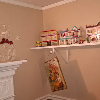 Sale Photo Thumbnail #118: Collection of assembled LEGO Friends sets and dollhouses displayed on a shelf, along with assorted holiday decor and vintage Barbie puzzle boxes on a mantle.