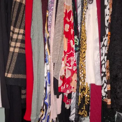 Sale Photo Thumbnail #69: Closet rack packed with an assortment of women's colorful knits, patterned tops, sweaters, and cardigans.