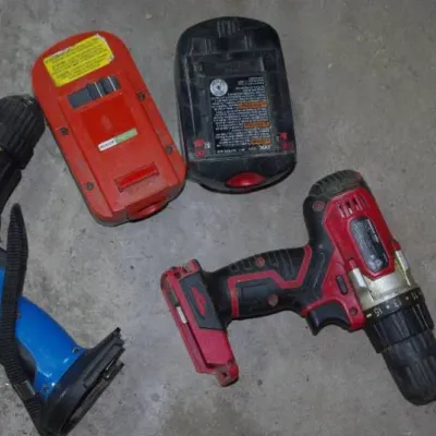 Collection of used cordless power tools, including a blue Drill Master 3/8-inch drill and a red cordless drill with accompanying...