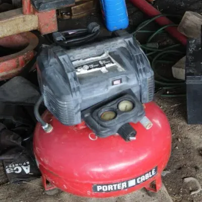 Porter-Cable 6-gallon pancake air compressor with attached dual gauges, showing light cosmetic wear and dust.