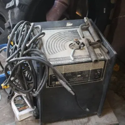 Vintage Sears Craftsman continuous control arc welder with cables and clamps, showing heavy surface wear.