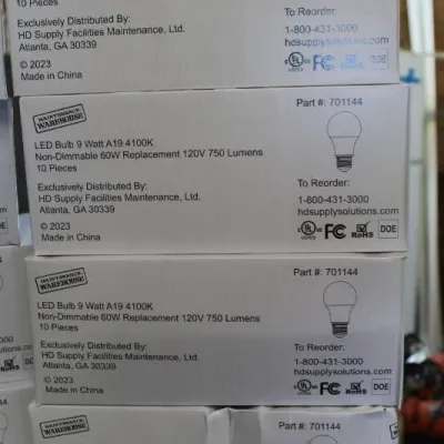 Stack of four 10-packs of Maintenance Warehouse 9-watt non-dimmable A19 LED light bulbs, copyright 2023.