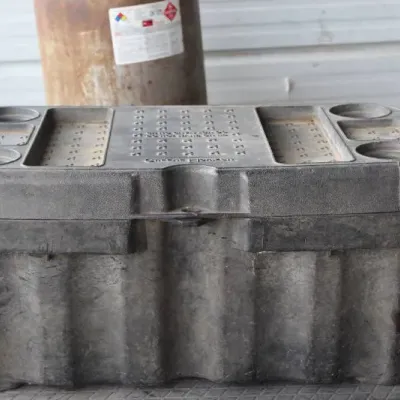 Heavy-duty black molded plastic storage box or cooler with molded cup holders on the lid, showing light dust and surface wear.