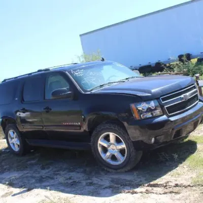 Black Chevrolet Suburban LT SUV featuring chrome wheels, roof rails, and tinted windows, parked outdoors.