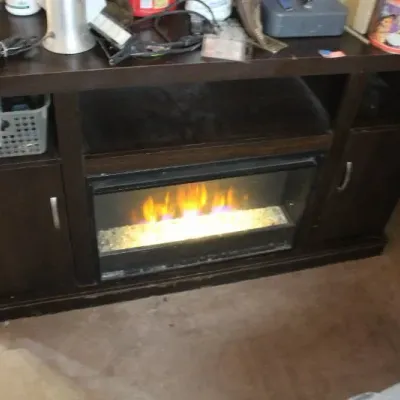 Modern dark brown media console featuring a central electric fireplace insert, open shelving, and side storage cabinets with silver handles.