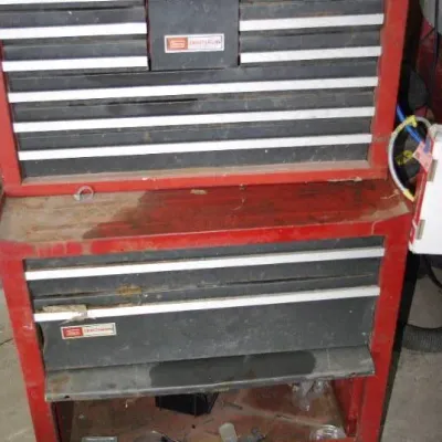 Vintage Craftsman red steel tool chest combo with top chest and rolling bottom cabinet, showing heavy surface wear and patina from use.