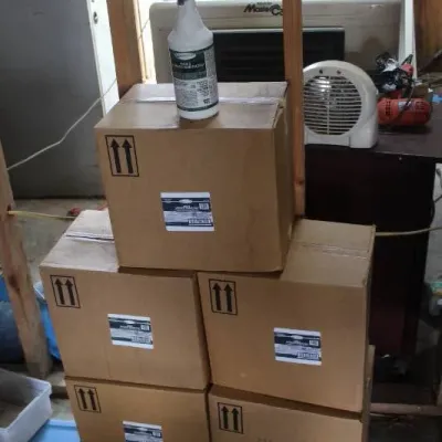 Stack of cardboard supply boxes topped with a white plastic spray bottle containing cleaning disinfectant.