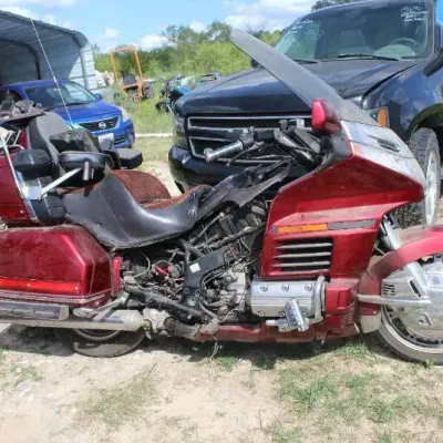 Damaged burgundy Honda Gold Wing touring motorcycle with missing body panels, offered for parts or repair.