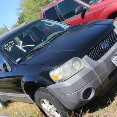 Black mid-2000s Ford Escape SUV parked outdoors on a grassy lot.