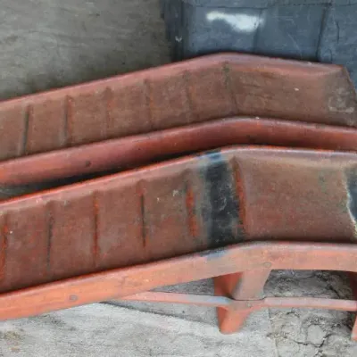 Pair of heavy-duty metal car service ramps in weathered orange finish with visible wear and surface rust.