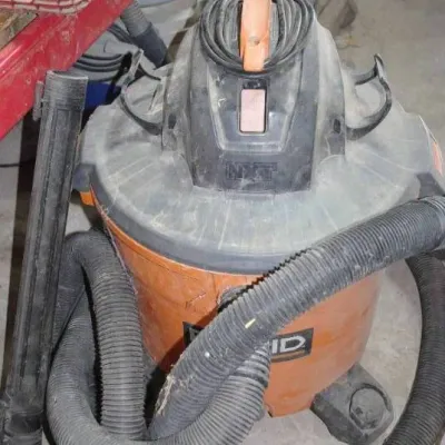 RIDGID NXT wet/dry shop vacuum in orange and black, complete with flexible hose, extension wand, and wrapped power cord.