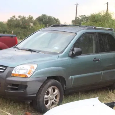 Mid-2000s Kia Sportage SUV in sage green, featuring roof rails and alloy wheels, parked outdoors.