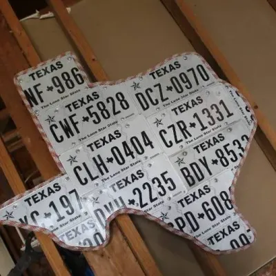 Handmade Texas state-shaped wall art constructed from pieced-together Texas license plates with a braided rope trim.
