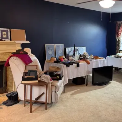 Sale Photo Thumbnail #16: white leather recliner,  framed art, glassware, hats, and collectibles, alongside a flat-screen television.