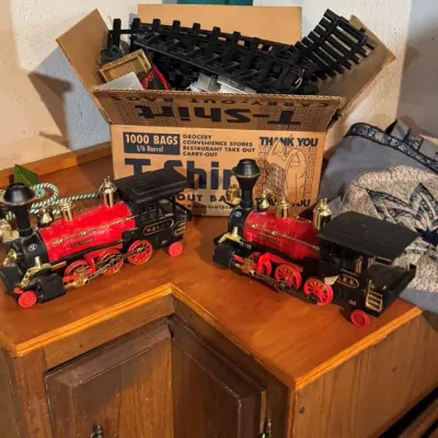Sale Photo Thumbnail #35: Two vintage-style plastic toy locomotive engines with brass-toned accents.