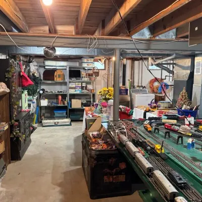 Sale Photo Thumbnail #15: O-gauge model train layout, metal storage shelving, bookcases, and various household goods.