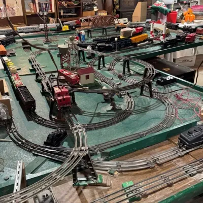 Sale Photo Thumbnail #34: Large vintage Lionel O-gauge model train layout featuring multi-level tracks, locomotives, freight cars, and scenery accessories.