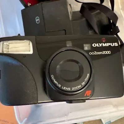 Sale Photo Thumbnail #27: Olympus Infinity Zoom 2000 35mm point-and-shoot film camera featuring an autofocus 38-70mm zoom lens and built-in flash, circa 1990s.