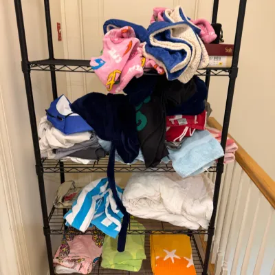 Sale Photo Thumbnail #77: Black metal wire shelving unit filled with assorted folded blankets, towels, and linens.