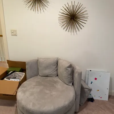 Sale Photo Thumbnail #79: Contemporary round swivel accent chair upholstered in light gray velvet, accompanied by two metal starburst wall sculptures mounted above.