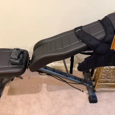 Sale Photo Thumbnail #49: Adjustable workout bench with black leatherette padding and red stitching, shown with an attached weighted vest.