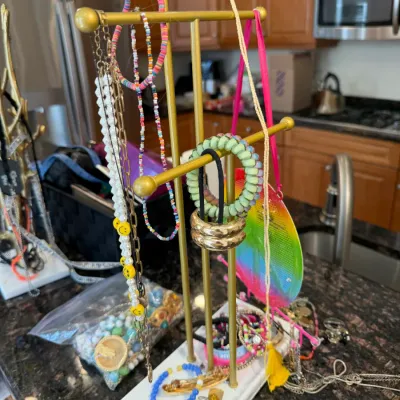 Sale Photo Thumbnail #29: Gold-tone metal T-bar jewelry stand with a white base, displaying a collection of beaded necklaces, bracelets, and hair accessories.