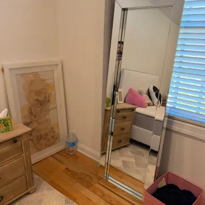 Sale Photo Thumbnail #60: Large contemporary mirrored floor mirror leaning against a bedroom wall beside a large framed abstract artwork.