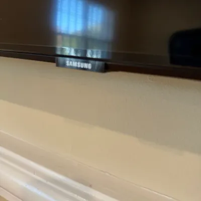 Sale Photo Thumbnail #38: Close-up of a Samsung flat-screen television mounted above a baseboard.