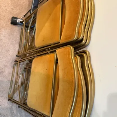 Sale Photo Thumbnail #48: Set of vintage folded metal card table chairs featuring gold-toned frames and light tan upholstered seats.
