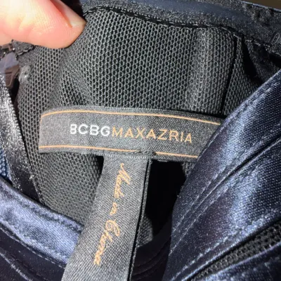 Sale Photo Thumbnail #72: Close-up of a BCBGMAXAZRIA designer brand tag attached to a navy blue garment.