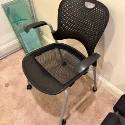 Sale Photo Thumbnail #50: Modern black mesh-seat office guest chair featuring a perforated plastic backrest, armrests, and silver metal legs on casters.