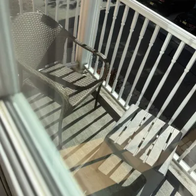 Sale Photo Thumbnail #53: Contemporary outdoor balcony set featuring a brown woven synthetic wicker armchair and a matching slatted grey side table.